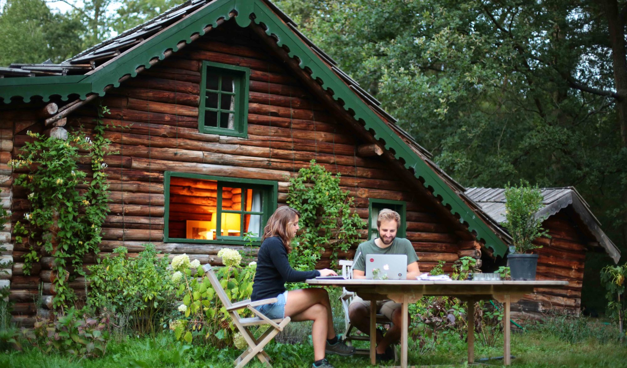 Un couple travaille dehors devant un gîte en bois